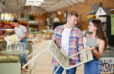 Cheerful couple evaluating patio chairs options in garden store