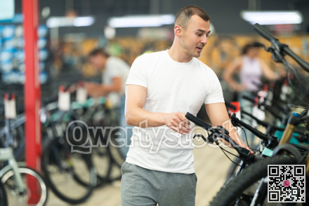 Excited man examining bike handlebar system in store