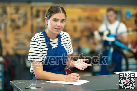 Friendly female mechanic completing service forms in bike repair shop