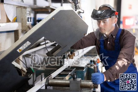 Workman cutting PVC profile on industrial machine in production workshop