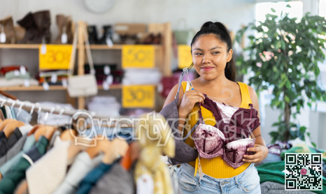 Happy young girl choosing bra in clothing store