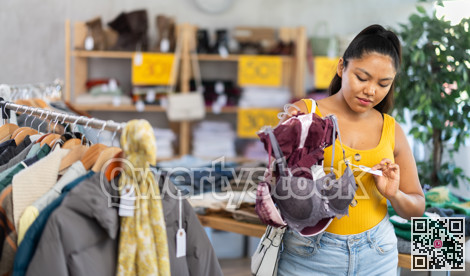 Attentive young girl choosing bra in clothing store