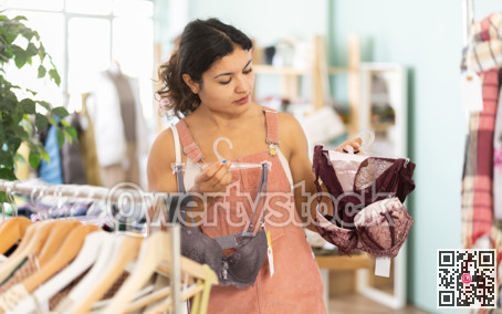Attentive young girl choosing bra in clothing store