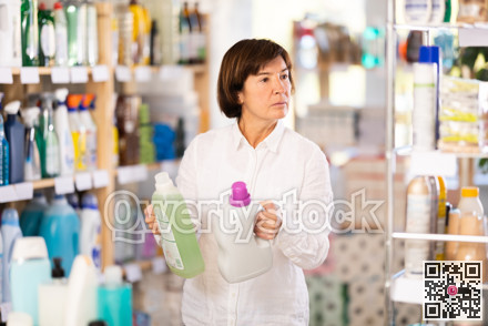 Elderly woman buyer chooses detergent in store