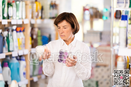 Elderly woman choosing scented candles in store