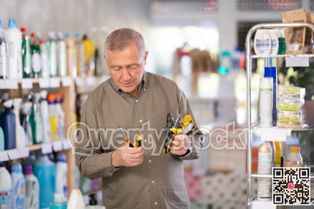 Man selects various tools - screwdrivers, pliers for repairs in supermarket