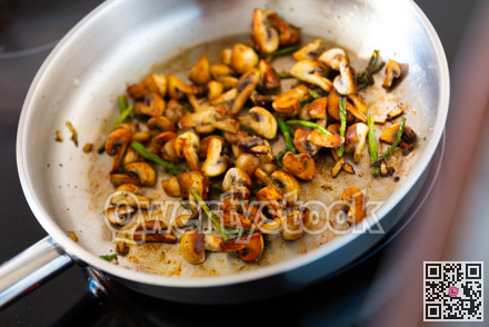 Finely chopped champignons and young asparagus shoots are fried in frying pan.