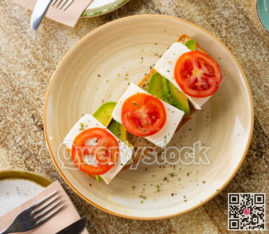 Open-faced sandwich with tomato, avocado, and cheese