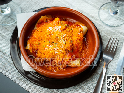 Delicious pasta cannelloni with meat and tomato sauce served in clay plate. Traditional Italian dish