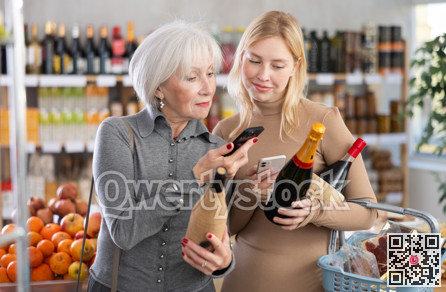 Elderly mother and her adult daughter scan a QR code on a bottle of wine label together to check expiration date