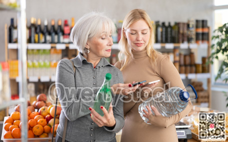 Girl and grandmother scan QR code, take reading drinking water label using phone camera in shop
