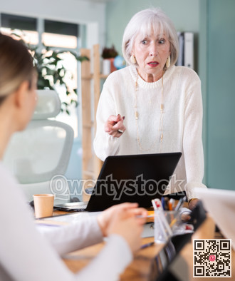 Elderly woman scolding female colleague working on tablet