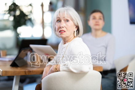 Two female colleagues are watching presentation in office room.