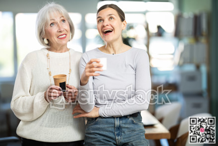 Two businesswomen drink coffee and discuss news during a break in office. Coffee break