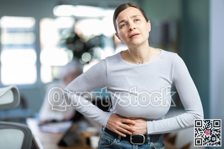 Adult woman with stomach pain during workday in office