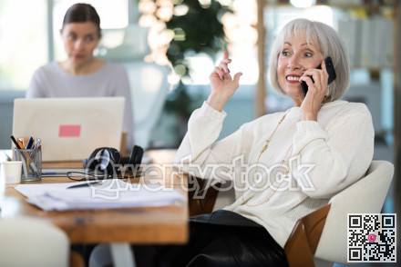 Adult woman judging female colleague talking on mobile phone