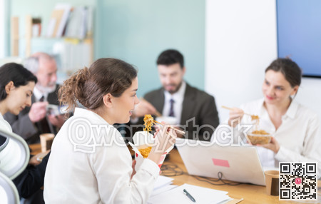 Group of colleagues, man and woman, are having lunch in office during their break, eating noodles