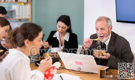 Office workers resting on break together eating, drinking coffee and talking, sitting at workplace at table with documents