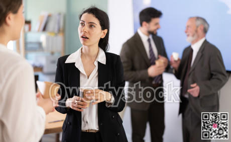 Two girls colleagues chat and laugh during coffee break