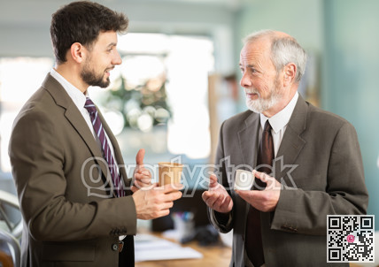 Two men colleagues chat and laugh during coffee break