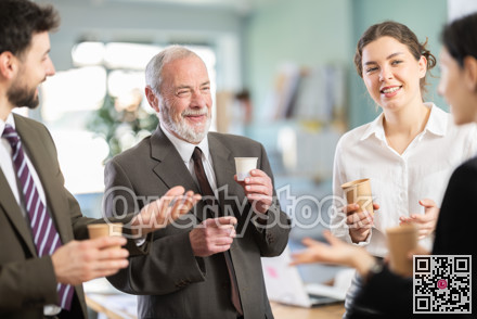 Friendly co-workers employees drinking hot coffee and talking during break while working in office