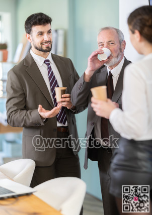 Coffee break - men and young woman drink coffee and chat lively with each other in modern office