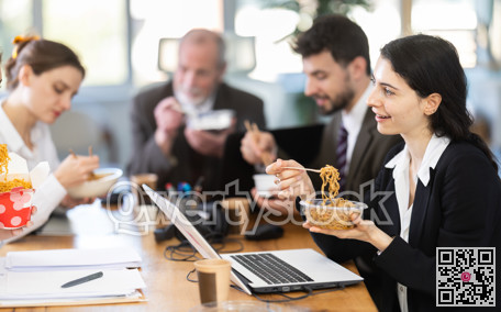 Lunch break - woman eating noodles with colleagues in modern office