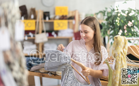 Girl chooses a set of clothes for summer. Visitor to the boutique examines the new summer collection of clothes