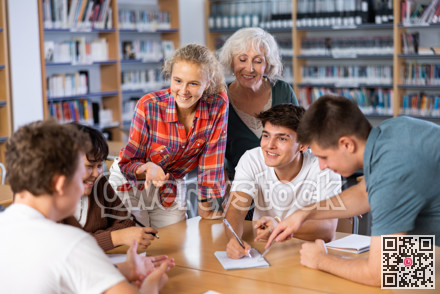 Classmates have fun chatting and telling each other in school library