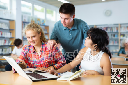 Three schoolchildren are studies on a laptop and taking abstracts in a copybook
