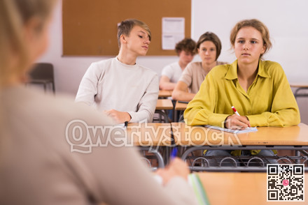 Group of students working at class, listening explanations of teacher in classroom