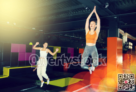 Excited woman enjoying jumping at well-equipped indoor trampoline arena