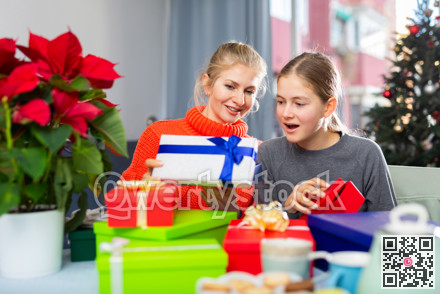 Woman and her daughter opens Christmas gift boxes