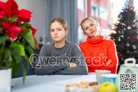 Schoolgirl sitting at the table after quarrel with mother