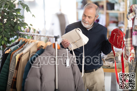 Elderly man chooses woman handbag as a gift in store