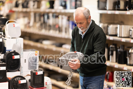 Senior man customer inspect product range and selects fan heater