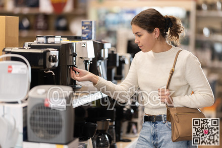 Young woman chooses coffee machine in appliance store