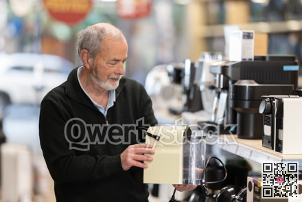 Elderly man chooses coffee machine in hypermarket
