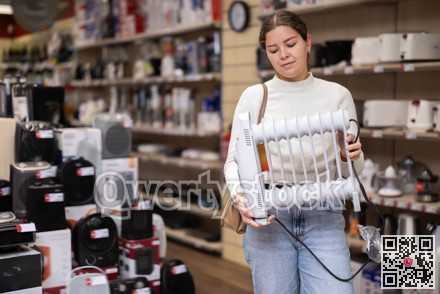 Young woman chooses oil heater in appliance store