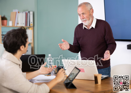 Young man working on tablet and elderly man on laptop in office