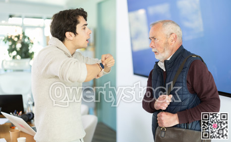 Young man scolding elderly male colleague for being late to office