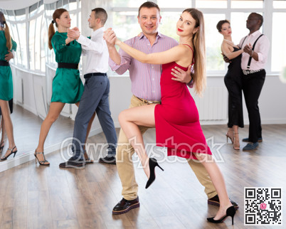Man and young woman practicing waltz in dancing studio