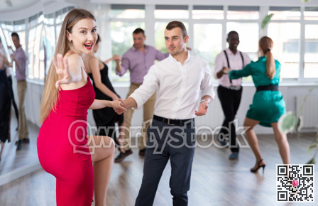 Woman and man dancing foxtrot in pair during group dance party
