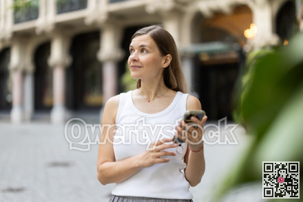 Female pedestrian with phone in summer European capital