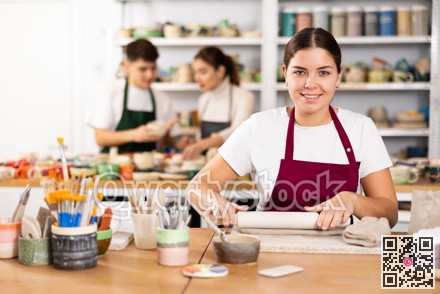 Woman rolling row clay with rolling-pin
