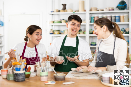 Joyous young man and women sculpting handmade cups
