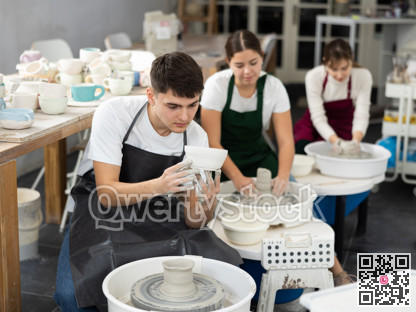 Young man holding clay bawl at pottery wheel