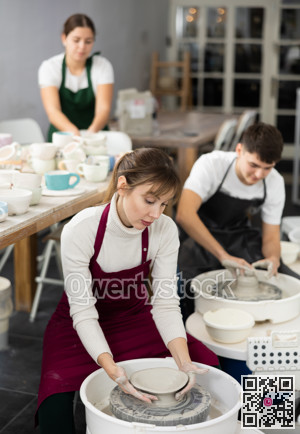 Young woman sculpting product on potter's wheel