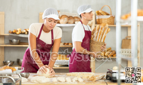 Young woman works in bakery as baker, kneads and prepare dough, works with flour.