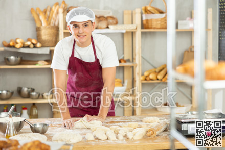 Male baker preparing raw yeast dough on kitchen table in bakery